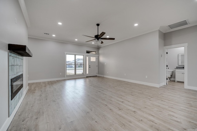 unfurnished living room featuring ceiling fan, ornamental molding, light wood-type flooring, and a fireplace