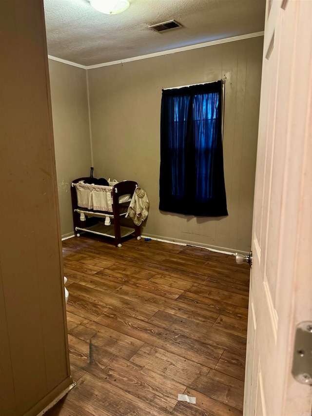 spare room with a textured ceiling, hardwood / wood-style flooring, and crown molding