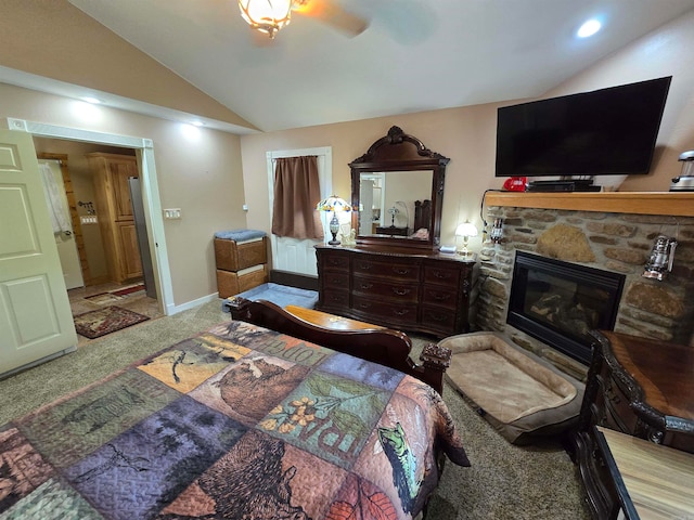 carpeted bedroom with a stone fireplace, ceiling fan, and lofted ceiling