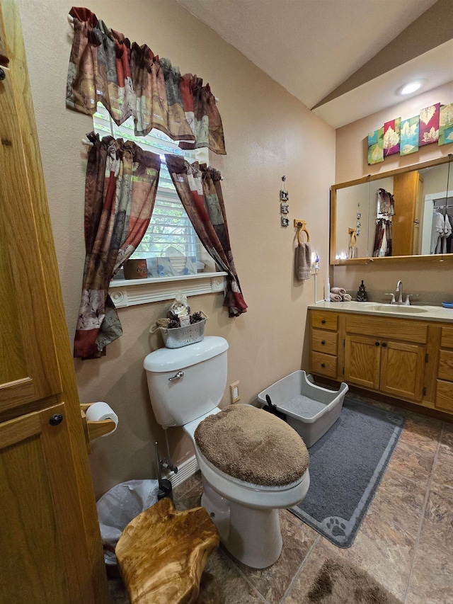 bathroom featuring tile flooring, vaulted ceiling, toilet, and vanity