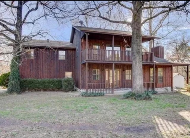 back of property featuring a yard and a balcony