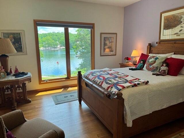 bedroom featuring hardwood / wood-style flooring and a water view