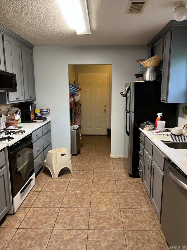 kitchen featuring a textured ceiling, gray cabinets, stainless steel appliances, and light tile patterned flooring