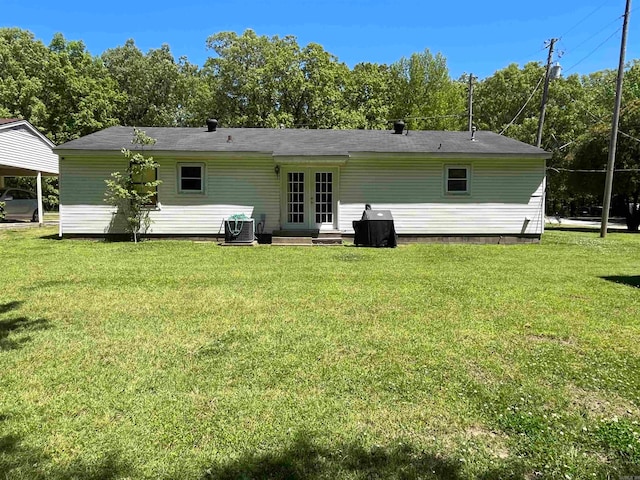 rear view of house with french doors, central AC, and a yard