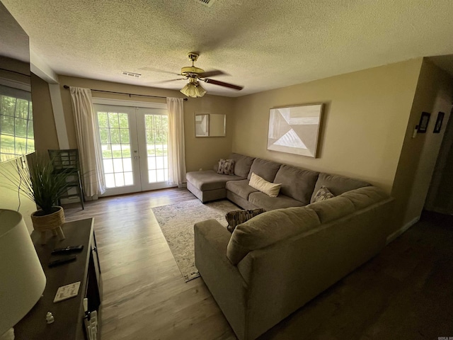 living room with ceiling fan, french doors, a textured ceiling, and wood-type flooring