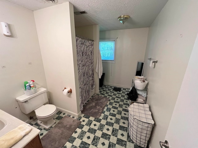 bathroom featuring tile flooring, toilet, and a textured ceiling