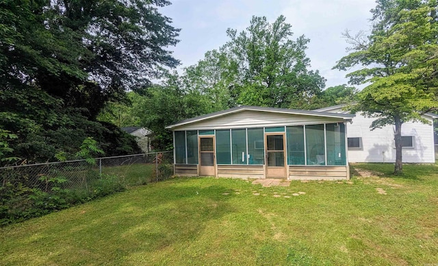 back of house with a sunroom and a lawn