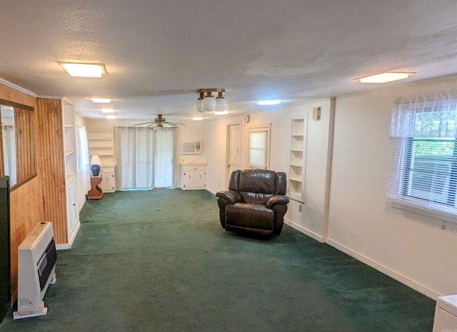 living area with built in features, crown molding, a textured ceiling, dark colored carpet, and ceiling fan