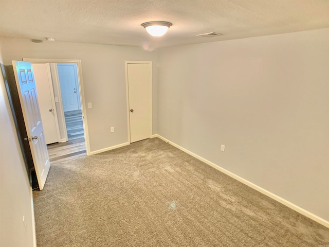 unfurnished room with a textured ceiling and carpet floors