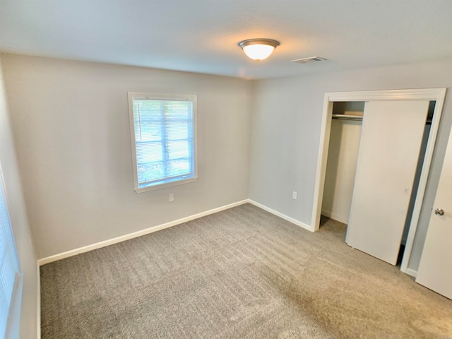 unfurnished bedroom featuring light colored carpet and a closet