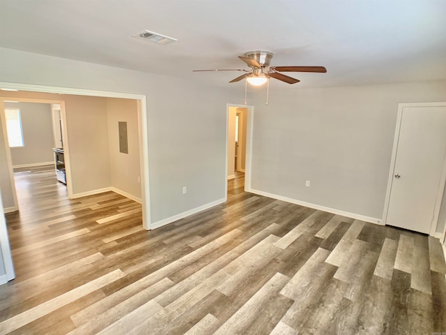 empty room featuring hardwood / wood-style flooring, ceiling fan, and electric panel