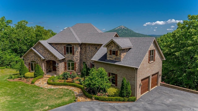 view of front of home featuring a garage, a mountain view, and a front lawn