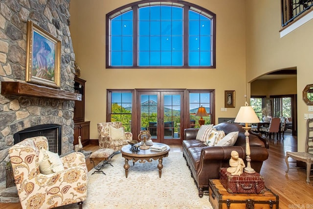 living room featuring a fireplace, a towering ceiling, and hardwood / wood-style floors