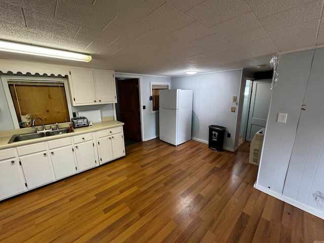 kitchen with sink, white cabinetry, white fridge, and hardwood / wood-style flooring