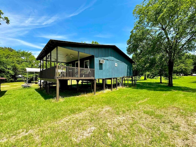 rear view of property with a wall unit AC, a wooden deck, and a lawn