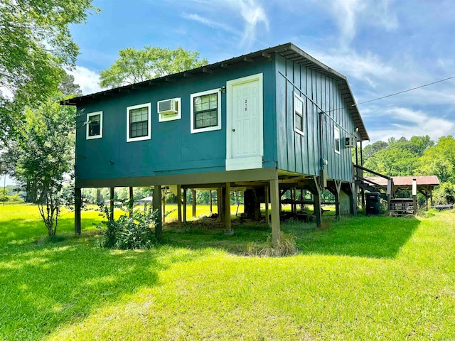 rear view of property featuring a wall mounted AC and a lawn