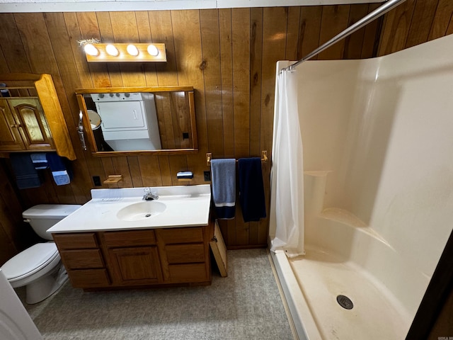 bathroom with washer / dryer, curtained shower, wood walls, toilet, and vanity