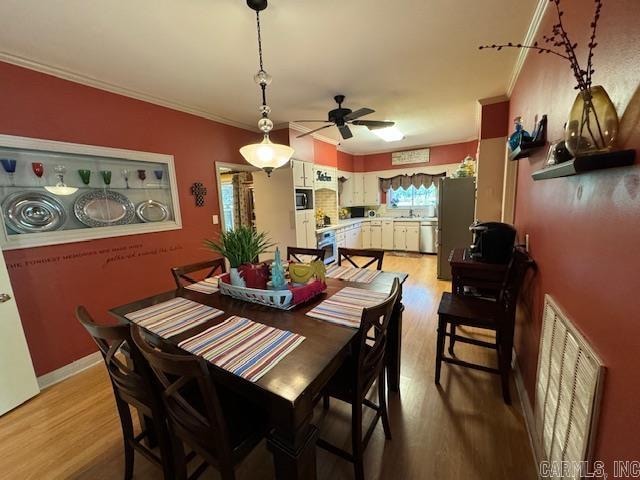 dining area featuring ceiling fan, hardwood / wood-style flooring, and crown molding