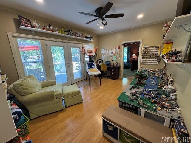 living room with french doors, ornamental molding, ceiling fan, and light wood-type flooring