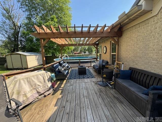 wooden terrace featuring outdoor lounge area, a pergola, and a shed