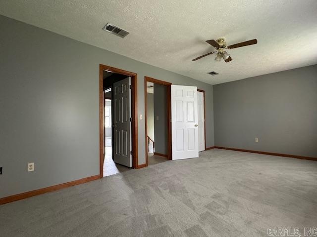 unfurnished room featuring a textured ceiling, carpet, and ceiling fan