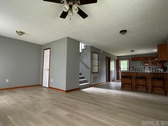 unfurnished living room with wood-type flooring, ceiling fan, and a textured ceiling