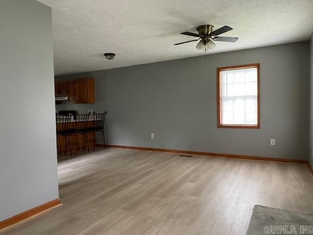 unfurnished living room with ceiling fan, a textured ceiling, and hardwood / wood-style flooring