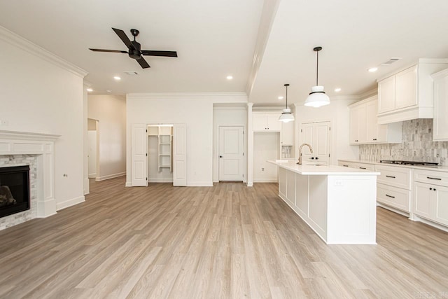 kitchen with a kitchen island with sink, a tile fireplace, and light wood-type flooring