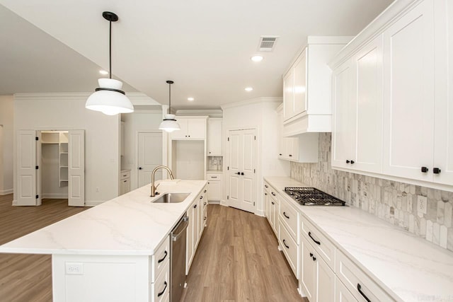 kitchen with light hardwood / wood-style flooring, a center island with sink, backsplash, sink, and white cabinets