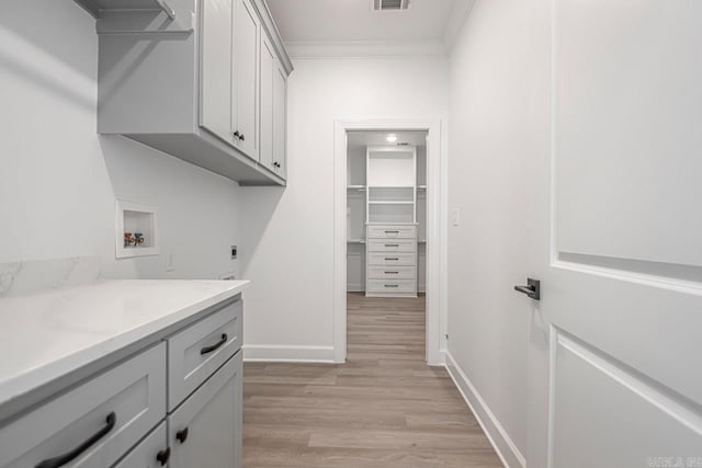 laundry room with cabinets, light hardwood / wood-style flooring, washer hookup, ornamental molding, and hookup for an electric dryer