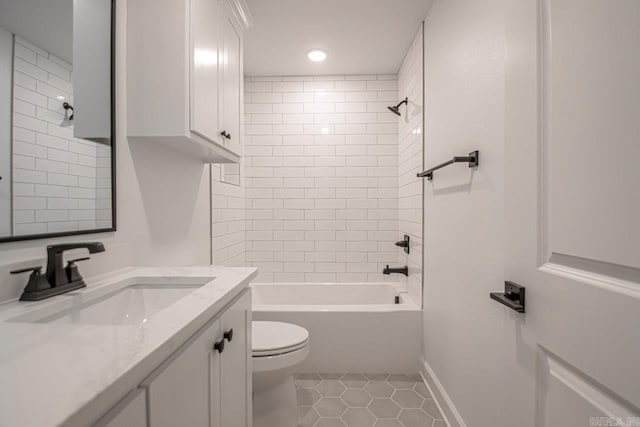 full bathroom with tiled shower / bath, tile flooring, vanity with extensive cabinet space, and toilet