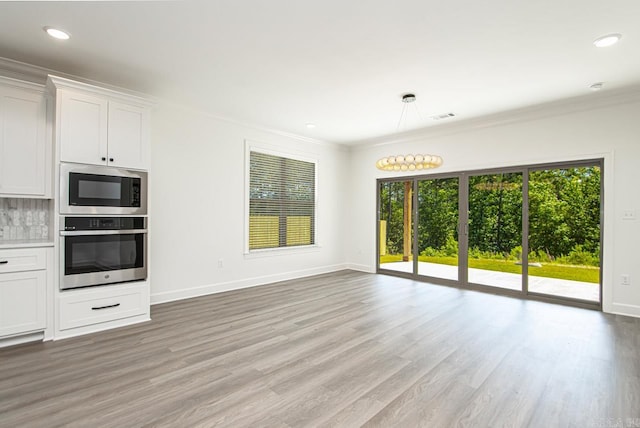 kitchen with wood-type flooring, white cabinetry, black microwave, and stainless steel oven