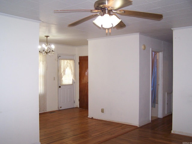 empty room featuring dark hardwood / wood-style floors, ornamental molding, and ceiling fan with notable chandelier