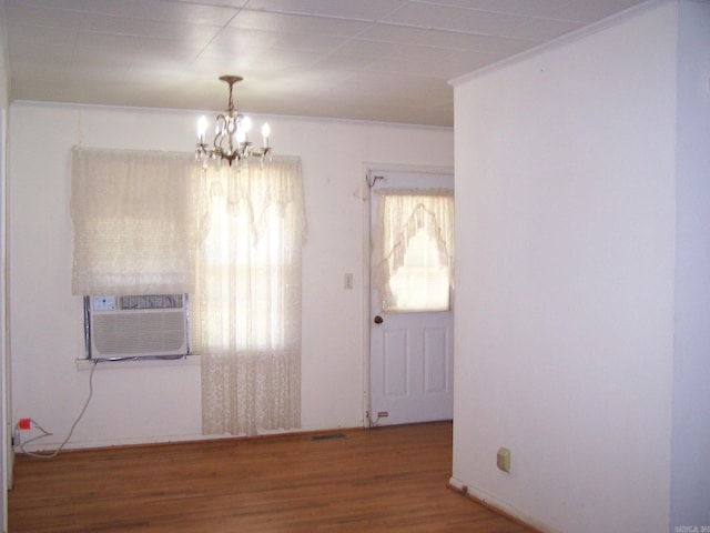 unfurnished room with a healthy amount of sunlight, hardwood / wood-style floors, and a chandelier