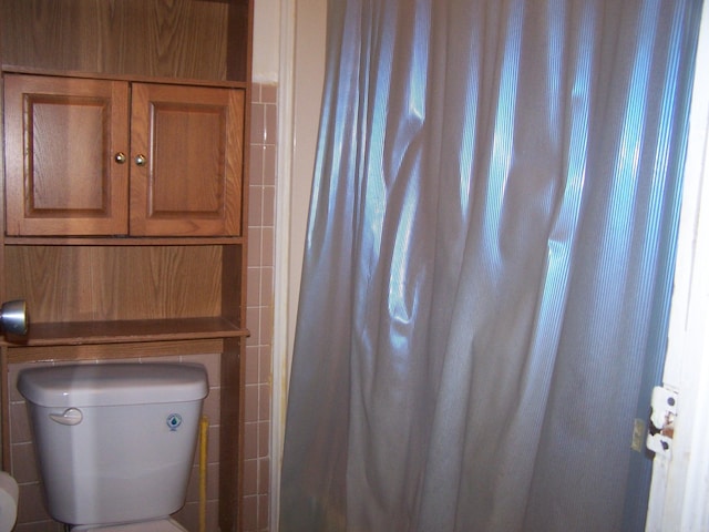 bathroom with tile walls and toilet