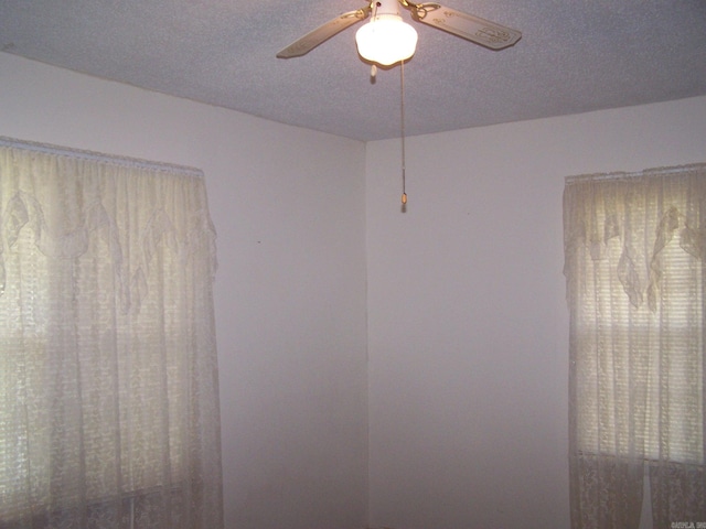 interior space with a textured ceiling and ceiling fan