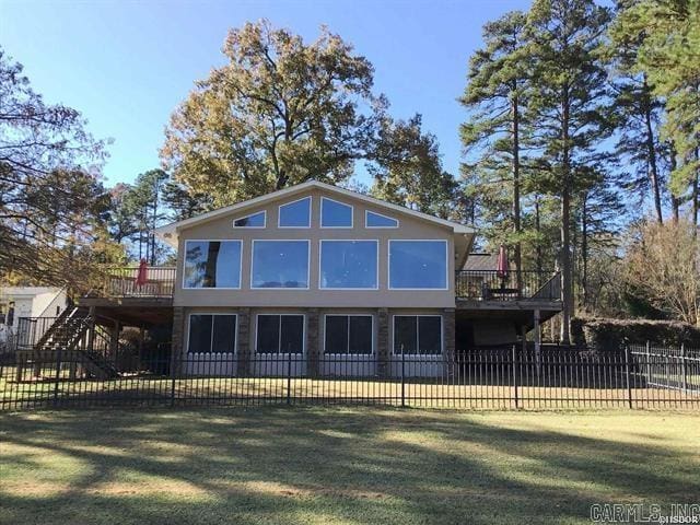 rear view of property featuring a lawn and a deck