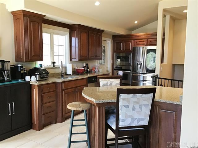 kitchen featuring a kitchen bar, light stone countertops, stainless steel appliances, vaulted ceiling, and sink