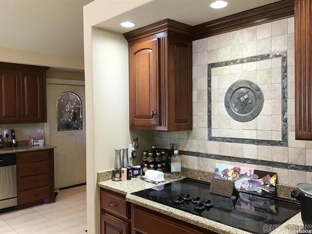 kitchen with light stone countertops, stainless steel dishwasher, decorative backsplash, black electric stovetop, and light tile patterned floors