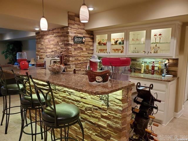 bar with white cabinets, decorative backsplash, decorative light fixtures, and stone countertops