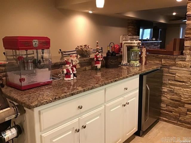 bar with light tile patterned flooring, white cabinetry, beverage cooler, and dark stone countertops
