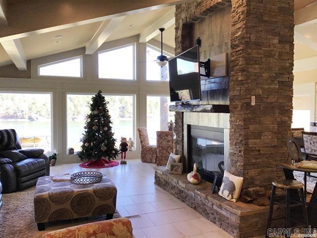 tiled living room featuring vaulted ceiling with beams and a stone fireplace