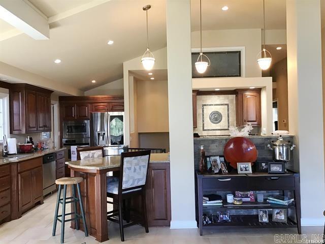 kitchen with tasteful backsplash, a breakfast bar, stainless steel appliances, vaulted ceiling, and hanging light fixtures