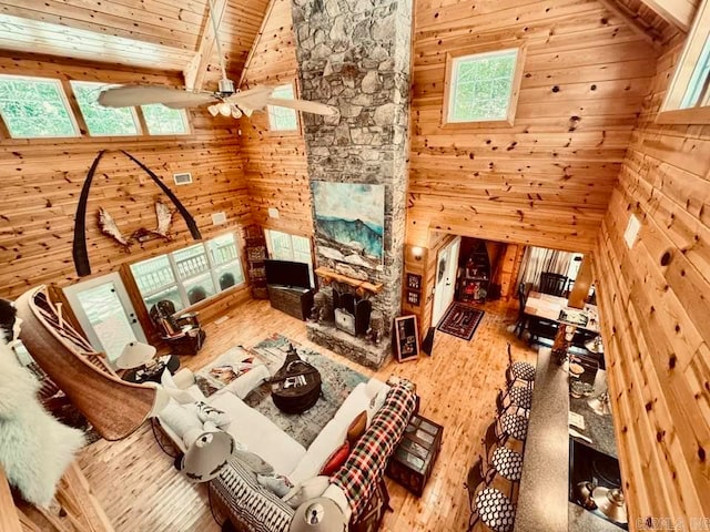 living room featuring wooden walls, ceiling fan, hardwood / wood-style floors, and beam ceiling