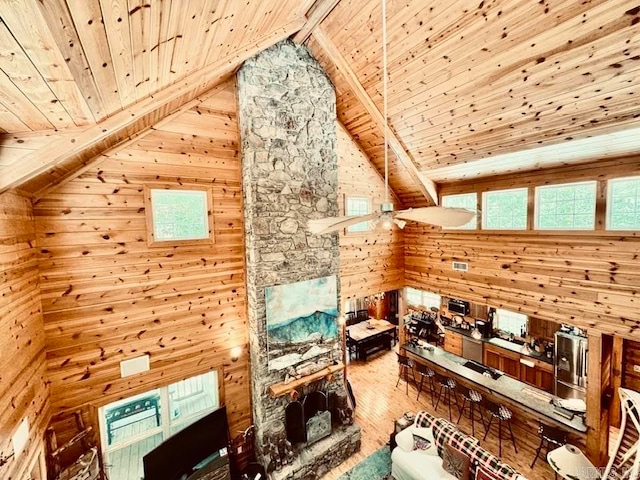 interior space with light hardwood / wood-style floors, beam ceiling, wooden walls, a healthy amount of sunlight, and wooden ceiling