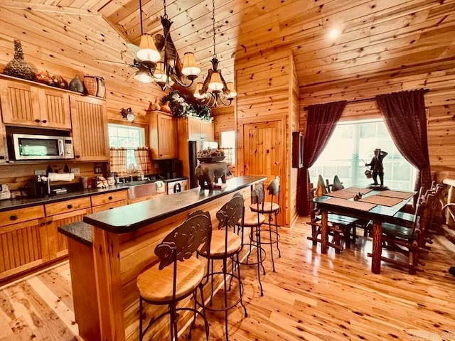 kitchen with light hardwood / wood-style flooring, wood walls, and decorative light fixtures