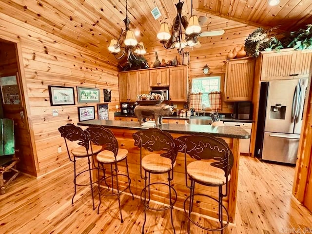 kitchen with stainless steel appliances, light hardwood / wood-style flooring, wood walls, pendant lighting, and wood ceiling