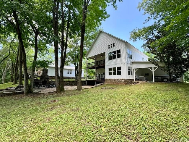 rear view of house featuring a carport and a yard