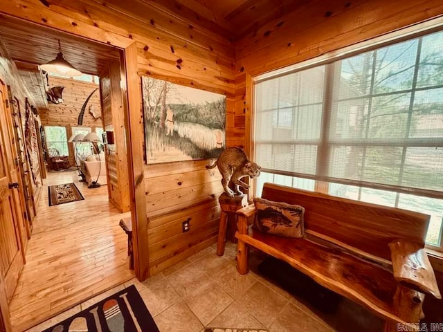 sitting room featuring wooden walls and light tile floors