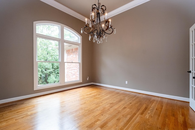 empty room featuring a notable chandelier, plenty of natural light, and light hardwood / wood-style flooring